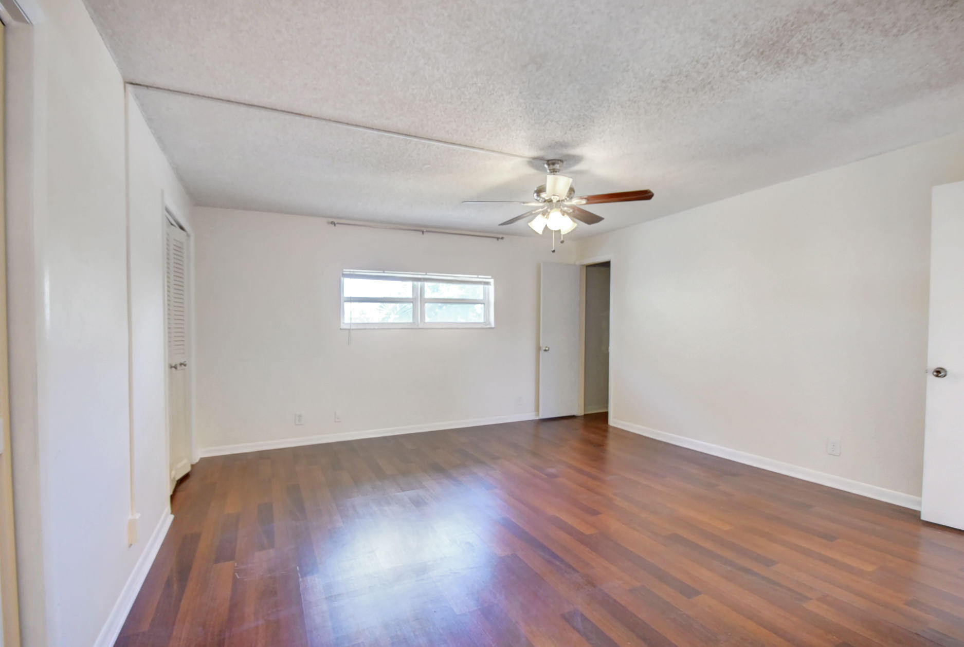 1845 Northwest 4th Avenue, Unit 16 Boca Raton, FL 33432 - Photo 30 of 37 an empty room with wooden floor and chandelier fan