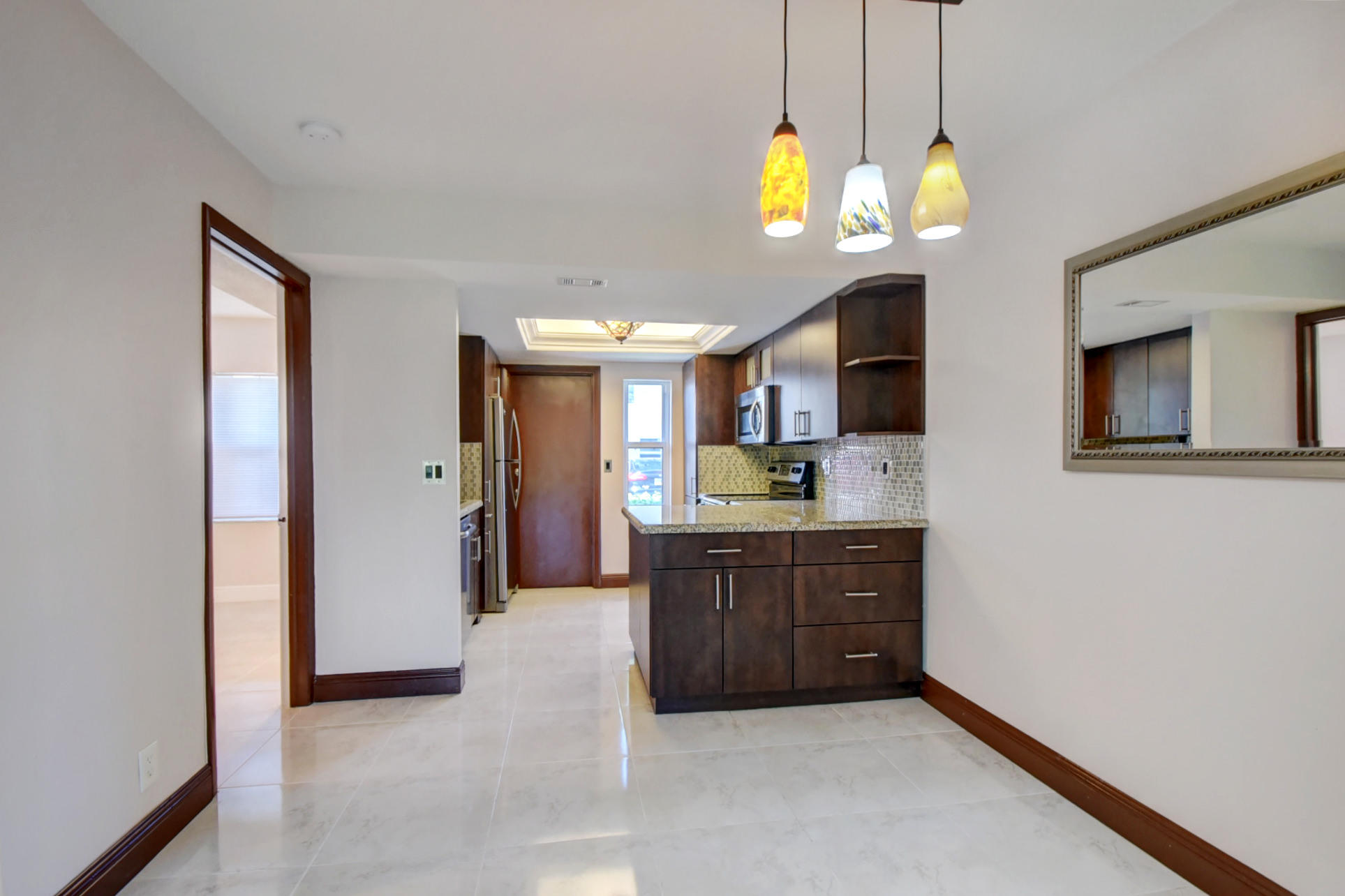 1845 Northwest 4th Avenue, Unit 16 Boca Raton, FL 33432 - Photo 5 of 37 a kitchen with stainless steel appliances granite countertop a refrigerator a sink dishwasher and a flat tv screen