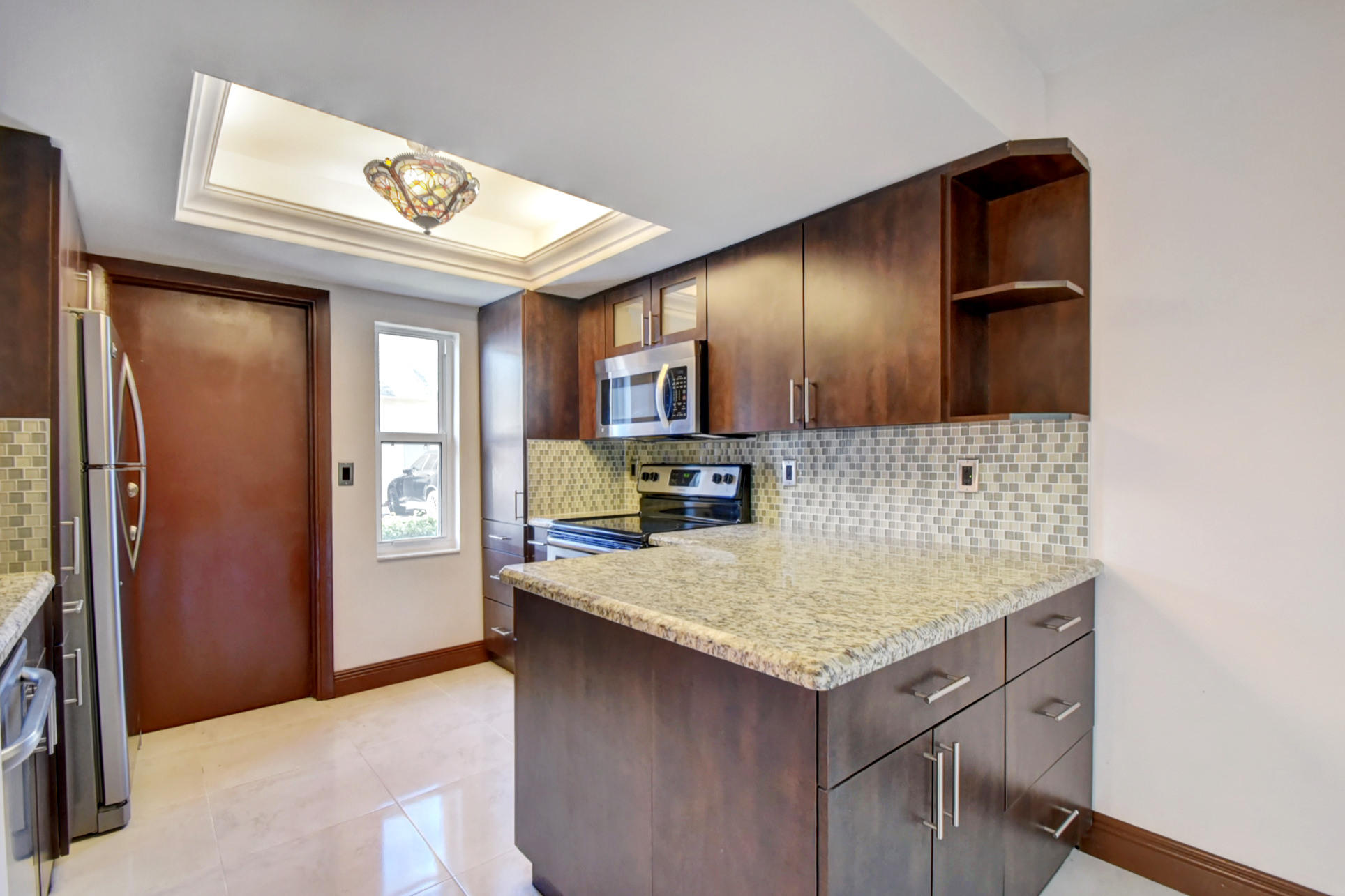 1845 Northwest 4th Avenue, Unit 16 Boca Raton, FL 33432 - Photo 10 of 37 a kitchen with a sink refrigerator and microwave