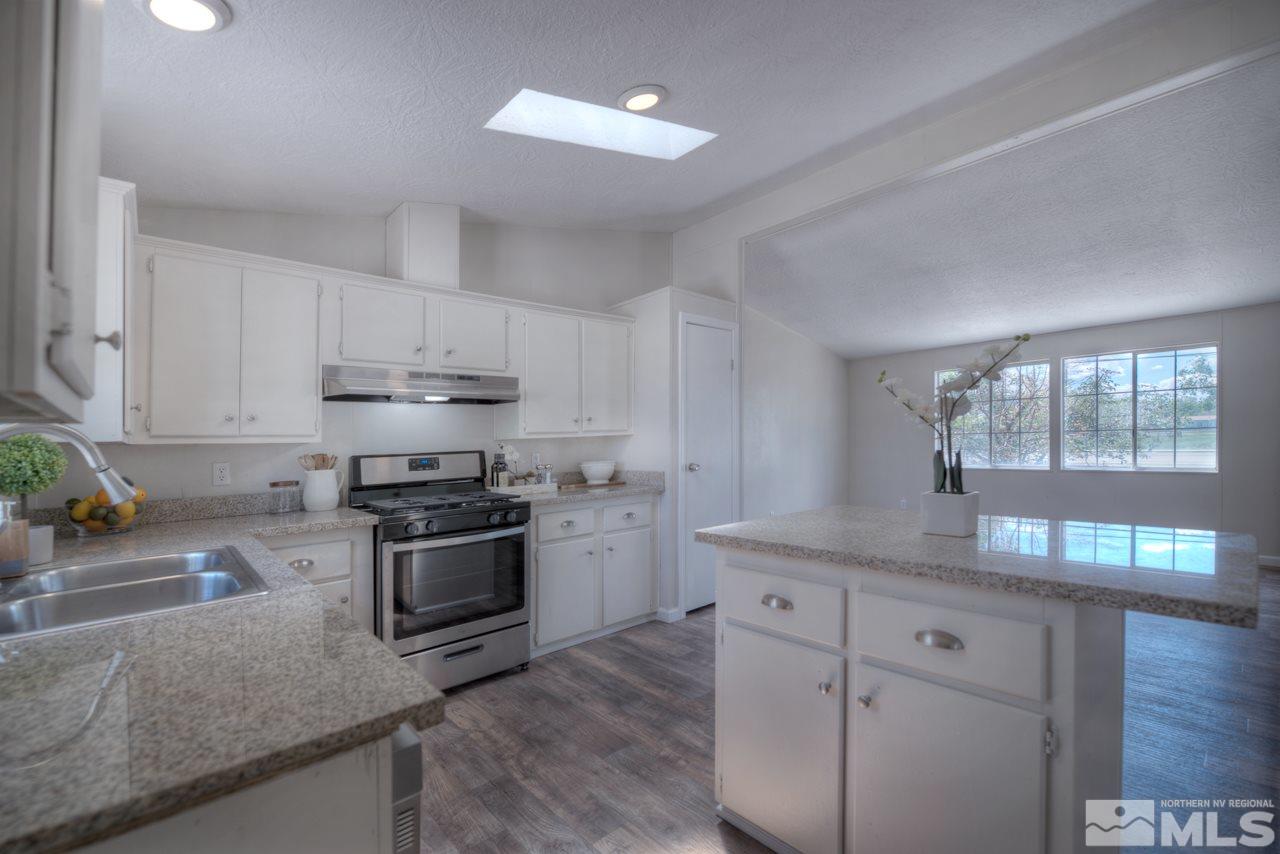 1380 Ricci Lane Fernley, NV 89408 - Photo 3 of 25 a kitchen with kitchen island granite countertop a sink cabinets and stainless steel appliances