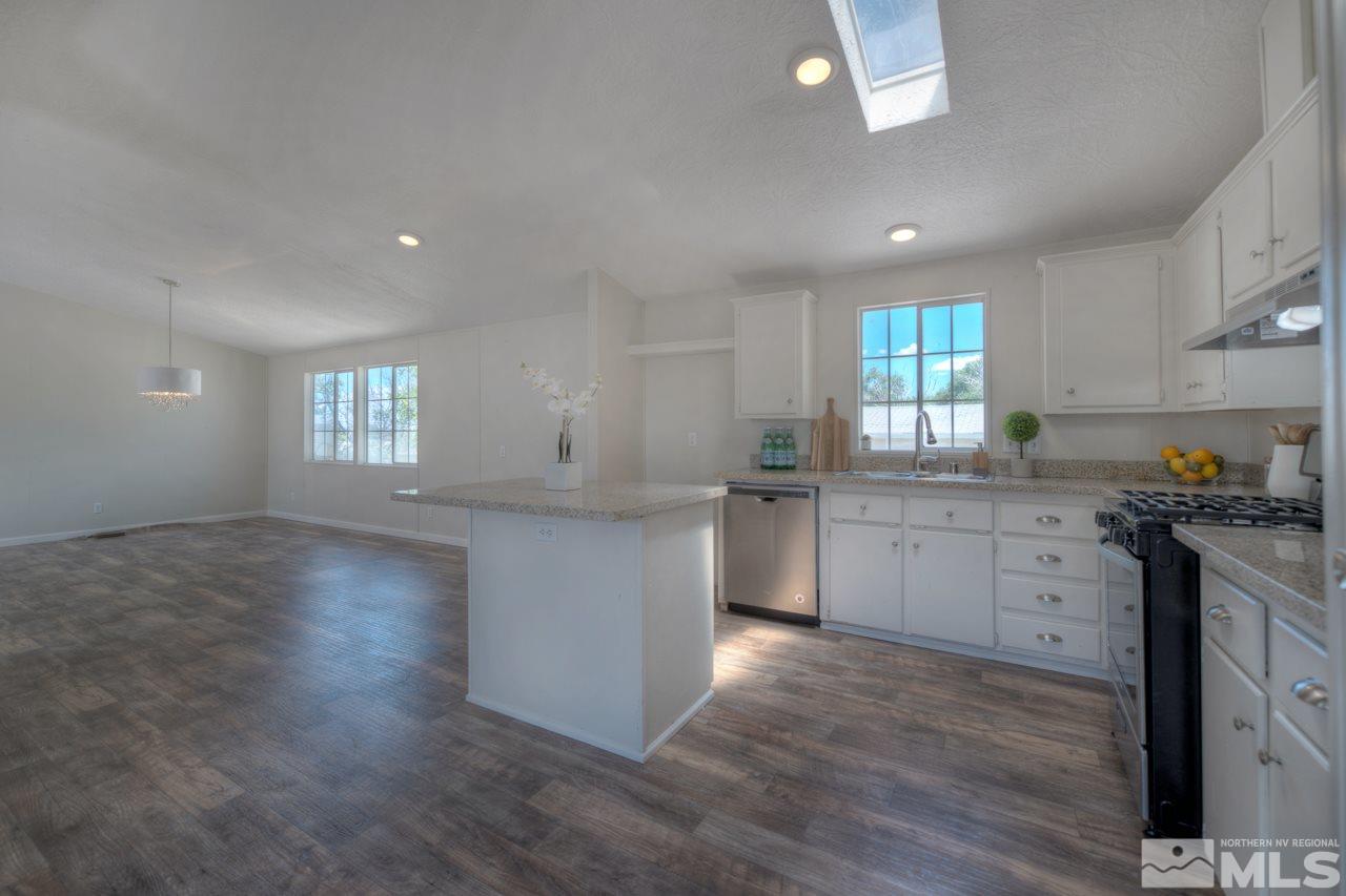 1380 Ricci Lane Fernley, NV 89408 - Photo 5 of 25 a kitchen with granite countertop white cabinets and white appliances