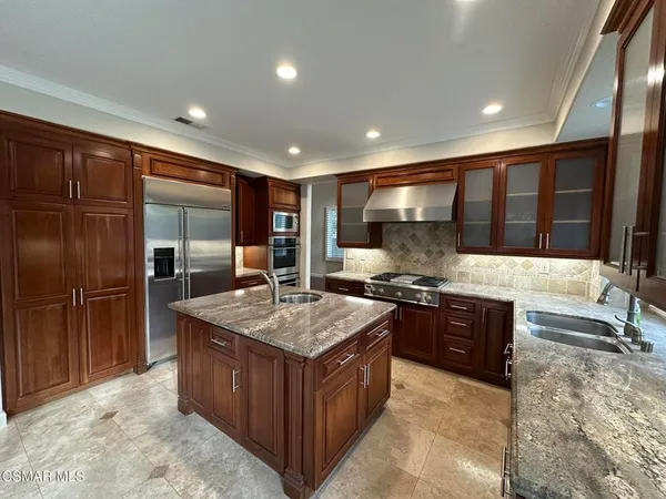 a kitchen with stainless steel appliances granite countertop wooden cabinets a sink a stove a refrigerator and a oven