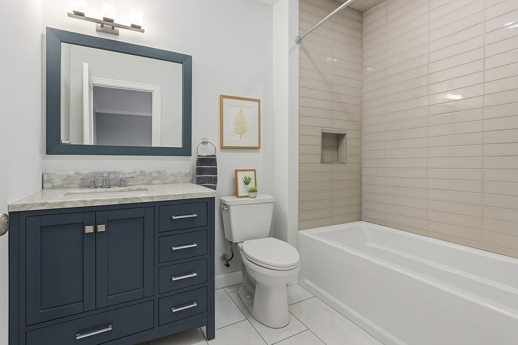 142 Pleasant Street, Unit 2 Winthrop, MA 02152 - Photo 11 of 14 a bathroom with a toilet a sink a bathtub and a mirror