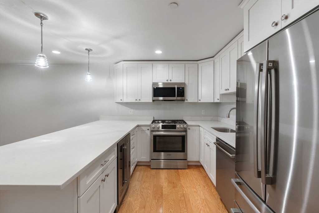 142 Pleasant Street, Unit 2 Winthrop, MA 02152 - Photo 6 of 14 a kitchen with a sink a counter top space stainless steel appliances and cabinets