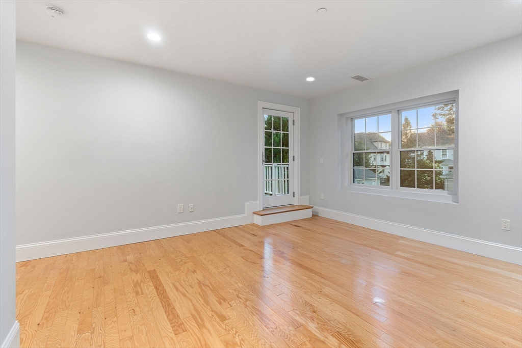 142 Pleasant Street, Unit 2 Winthrop, MA 02152 - Photo 9 of 14 an empty room with wooden floor and windows