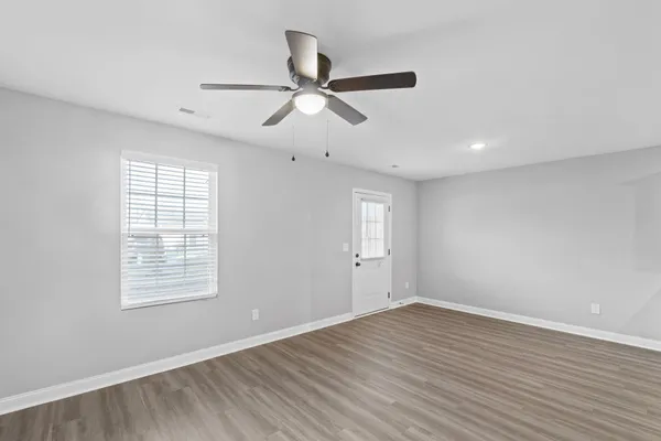 a view of empty room with wooden floor and fan