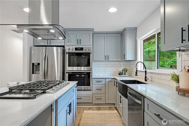 a kitchen with granite countertop a sink stainless steel appliances and white cabinets