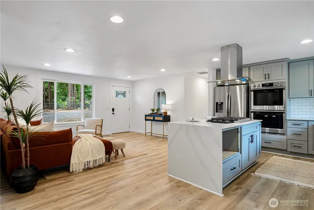 a large kitchen with stainless steel appliances granite countertop a stove oven and a refrigerator with the couches