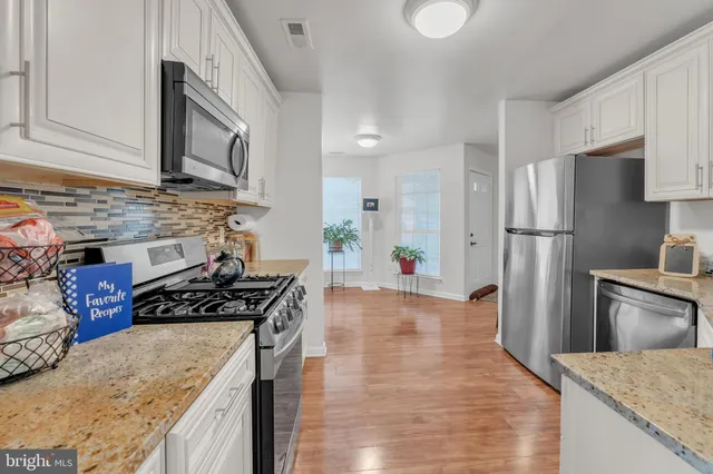 a kitchen with granite countertop white cabinets and stainless steel appliances