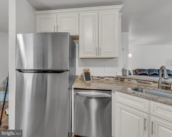 a kitchen with stainless steel appliances granite countertop a stove top oven a sink dishwasher and a microwave oven with wooden floor