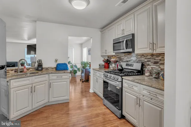 a kitchen with granite countertop a stove a sink and a refrigerator