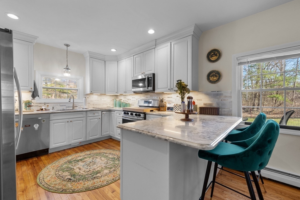 a kitchen with stainless steel appliances granite countertop a stove a sink a microwave a refrigerator and chairs