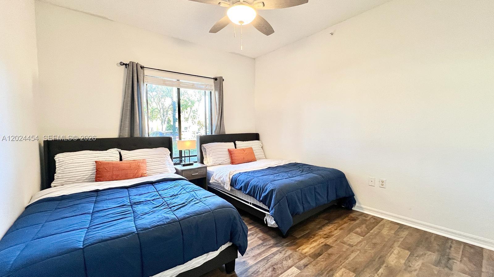2727 Anzio Court, Unit 106 Palm Beach Gardens, FL 33410 - Photo 24 of 43 a bedroom with two beds and a chandelier