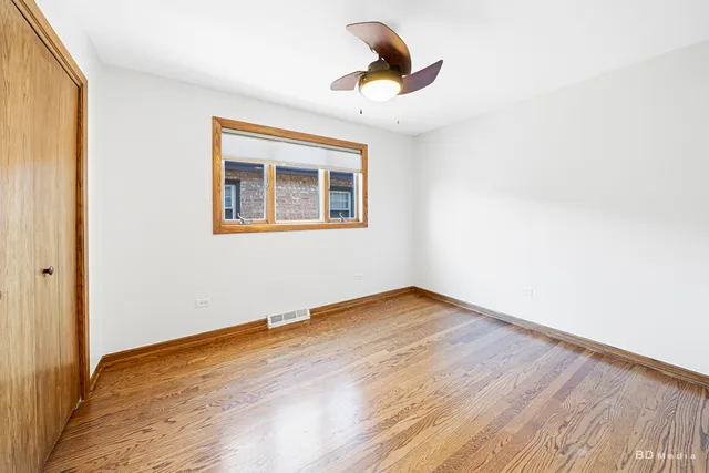 an empty room with wooden floor closet and fan