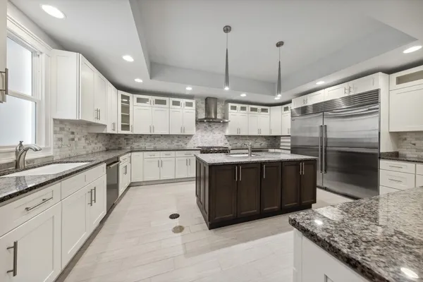 a kitchen with stainless steel appliances granite countertop a refrigerator a sink dishwasher a stove and white cabinets with wooden floor