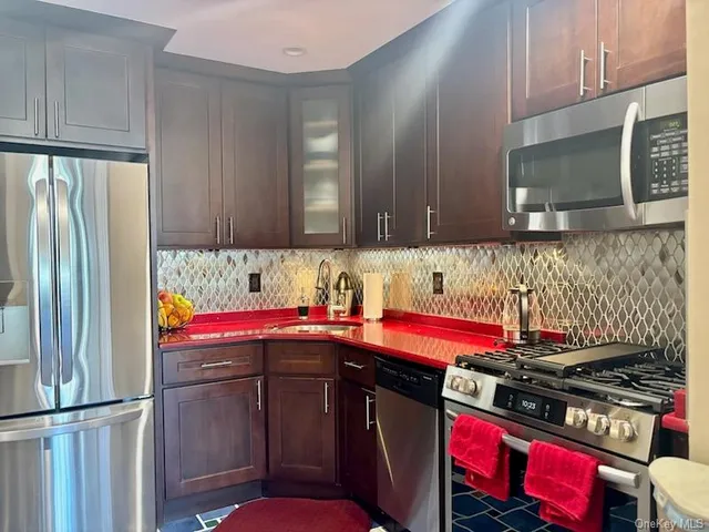 a kitchen with stainless steel appliances granite countertop a stove a sink and a microwave