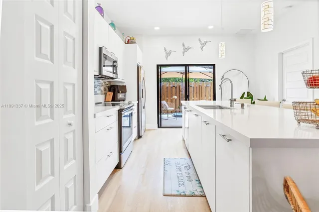a large white kitchen with stainless steel appliances granite countertop a lot of counter space and wooden floors