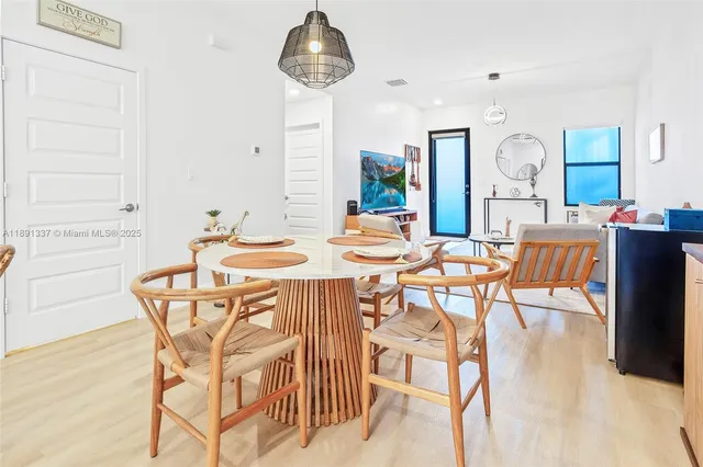 a dining room with wooden floor a chandelier a wooden table and chairs