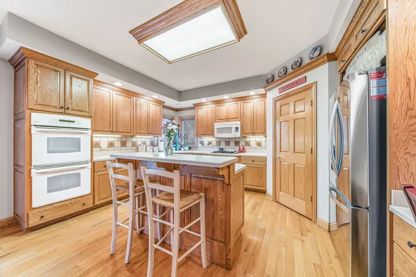 a kitchen with stainless steel appliances granite countertop a refrigerator and wooden cabinets