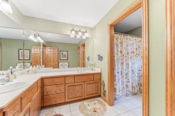 a spacious bathroom with a double vanity sink a mirror and a shower