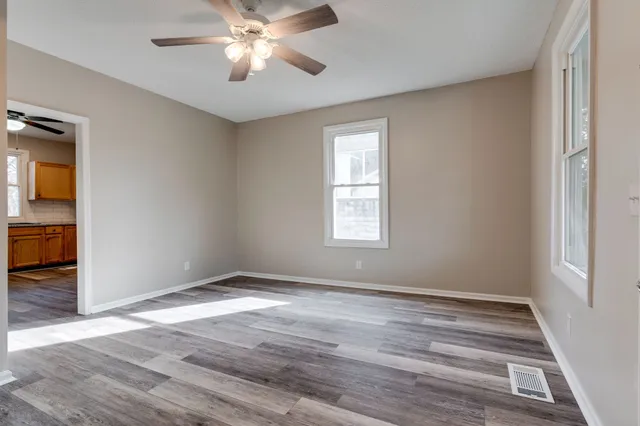 a view of empty room with wooden floor and fan