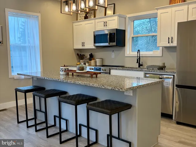 a kitchen with stainless steel appliances granite countertop a stove a sink dishwasher and a refrigerator with wooden cabinets