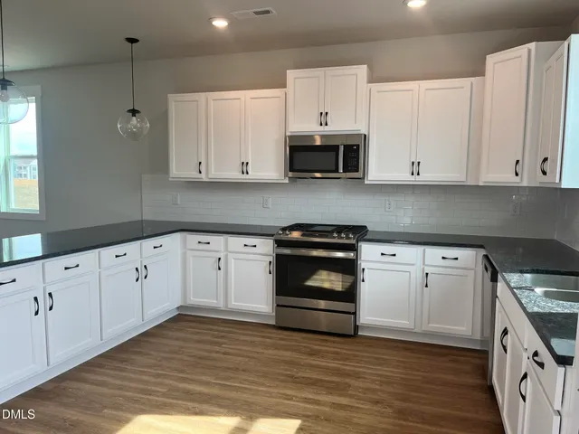 a kitchen with granite countertop white cabinets and stainless steel appliances