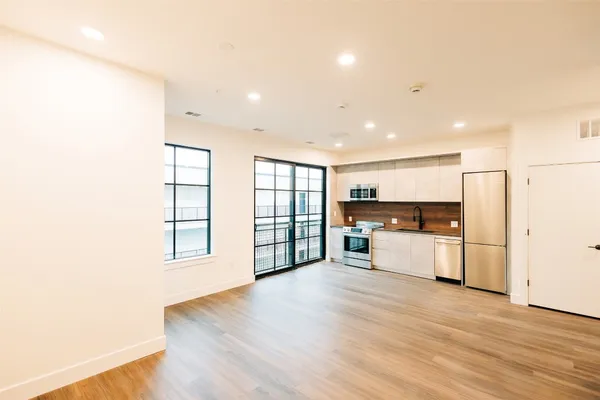 a large kitchen with stainless steel appliances wooden floor and a window