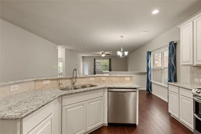 a kitchen with granite countertop wooden cabinets stainless steel appliances and a wooden floor