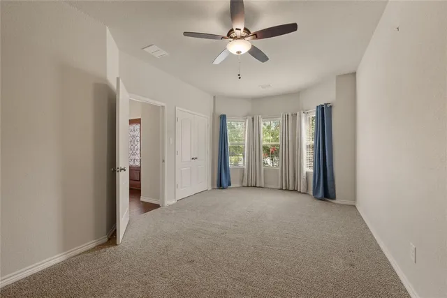 an empty room with chandelier fan and windows