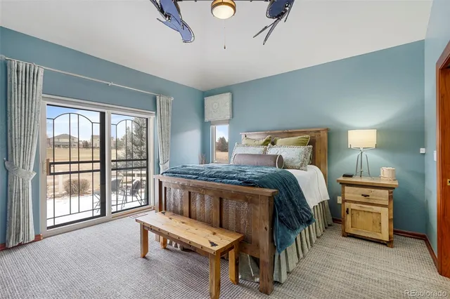 a bedroom with a bed a table and three large window