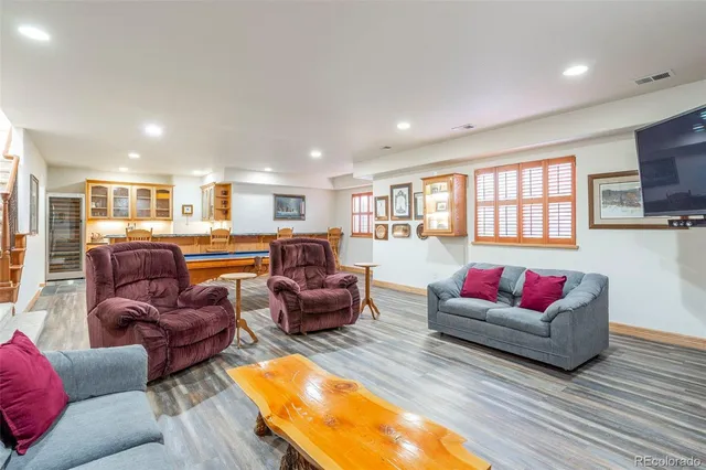 a living room with furniture kitchen view and a wooden floor