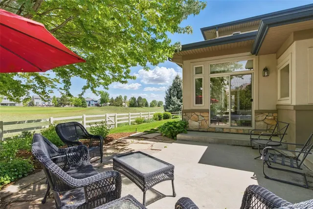 a view of a patio with couches table and chairs under an umbrella