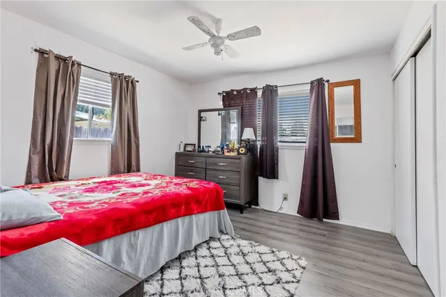 a bedroom with a bed and a dresser with wooden floor