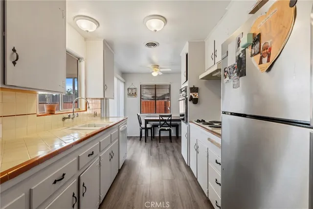 a kitchen with granite countertop a refrigerator a sink dishwasher a stove and a dining table with wooden floor