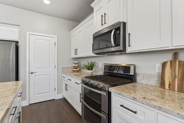 a kitchen with granite countertop white cabinets and stainless steel appliances
