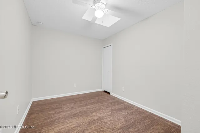 a view of a room with wooden floor and a ceiling fan