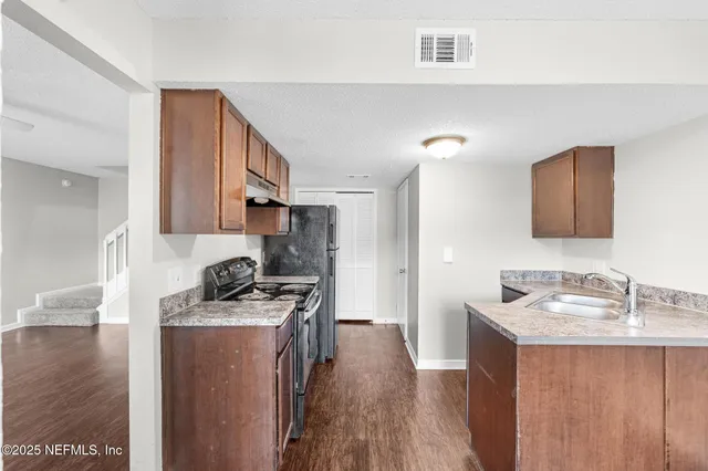 a kitchen that has a sink a stove and a refrigerator