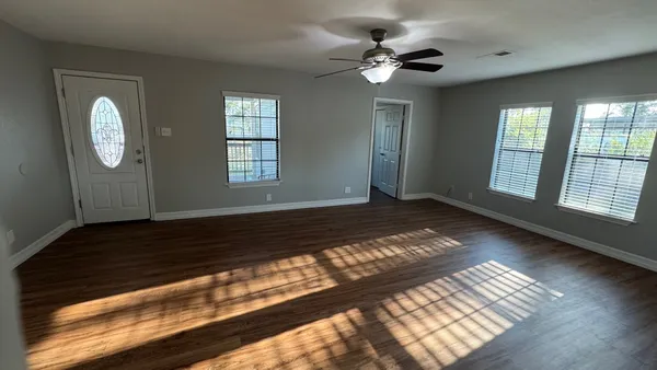 a view of an empty room with wooden floor and a window