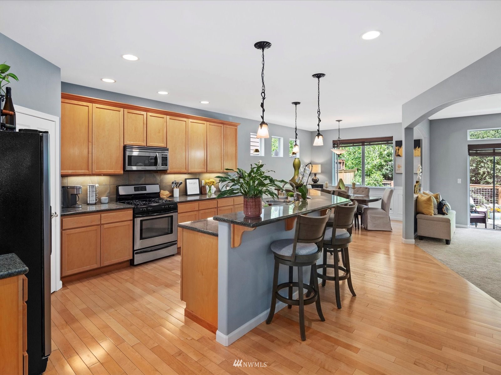 1705 235th Place Southwest Bothell, WA 98021 - Photo 4 of 35 a kitchen with stainless steel appliances kitchen island granite countertop a refrigerator a stove top oven a sink dishwasher and a dining table with wooden floor