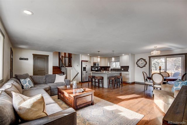 a living room with furniture kitchen view and a large window