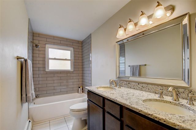 a bathroom with a granite countertop sink a toilet a mirror a bathtub and shower