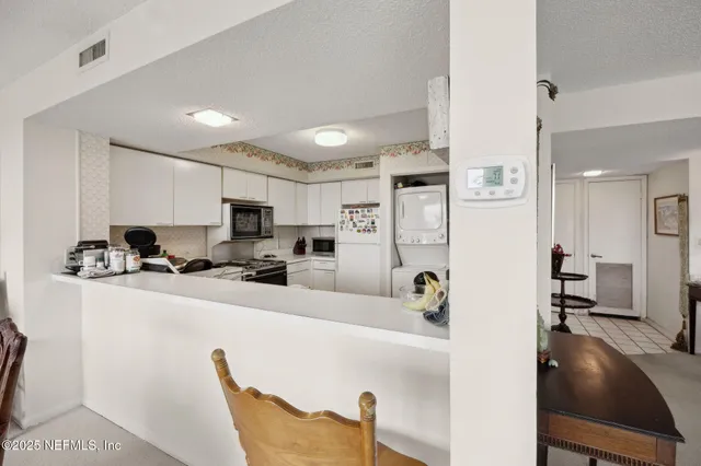 a kitchen with stainless steel appliances a refrigerator a sink a stove a table and chairs