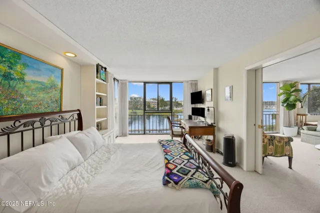 a bedroom with furniture a flat screen tv and a large window