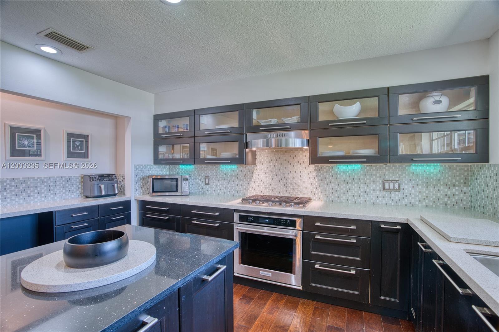16078 Mellen Lane Jupiter, FL 33478 - Photo 14 of 57 a kitchen with stainless steel appliances granite countertop a sink and wooden cabinets