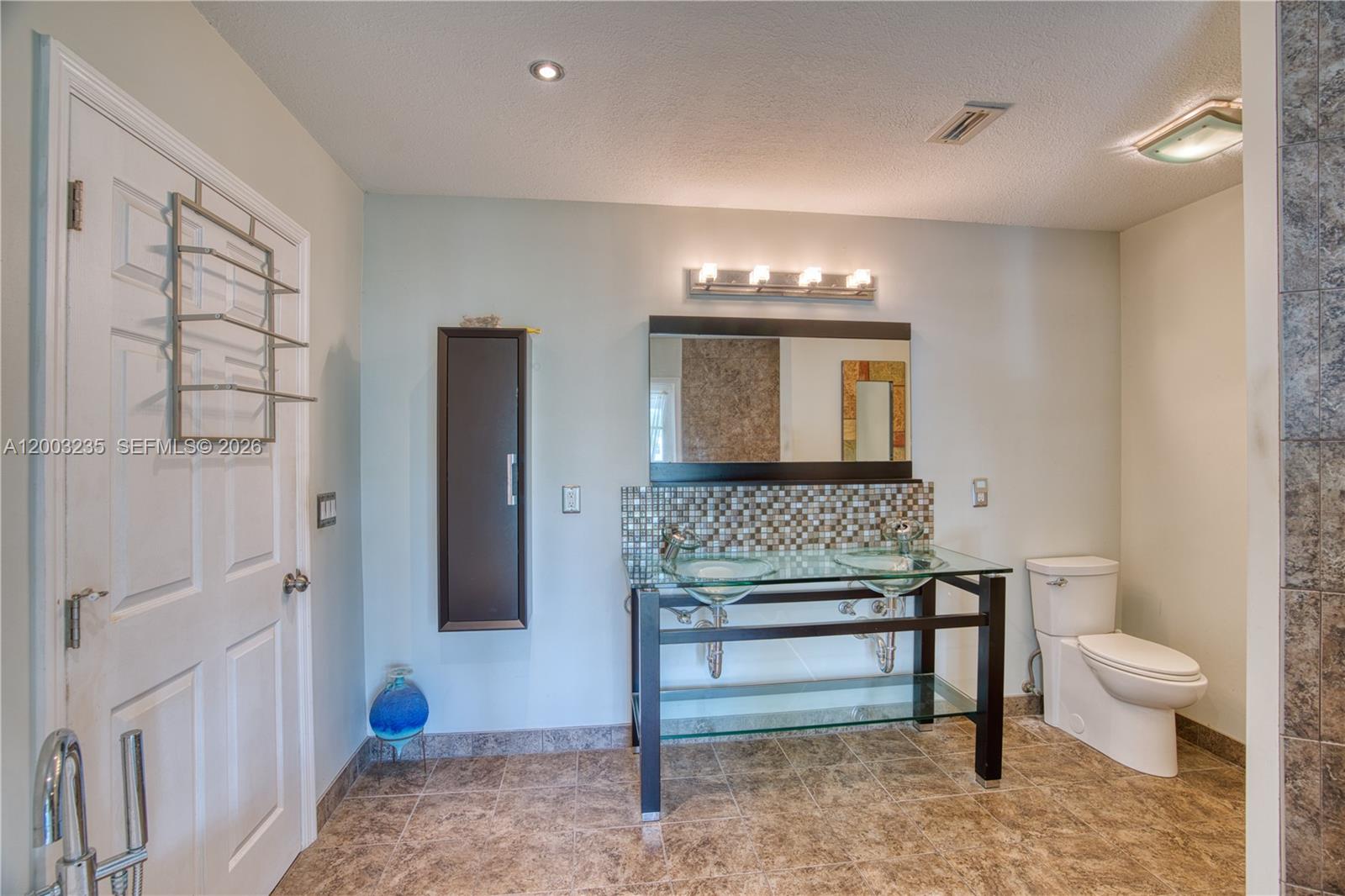 16078 Mellen Lane Jupiter, FL 33478 - Photo 24 of 57 a bathroom with a toilet a sink and a mirror