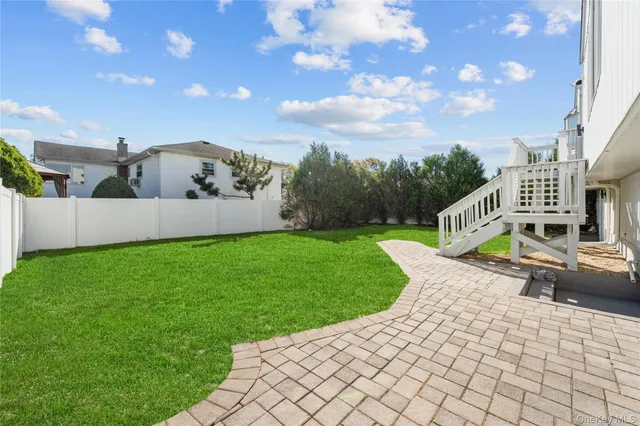 a view of a yard in front of a house with plants and large trees