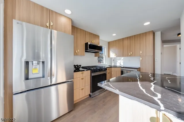 a kitchen with stainless steel appliances granite countertop a refrigerator a stove a sink a microwave and with wooden cabinets