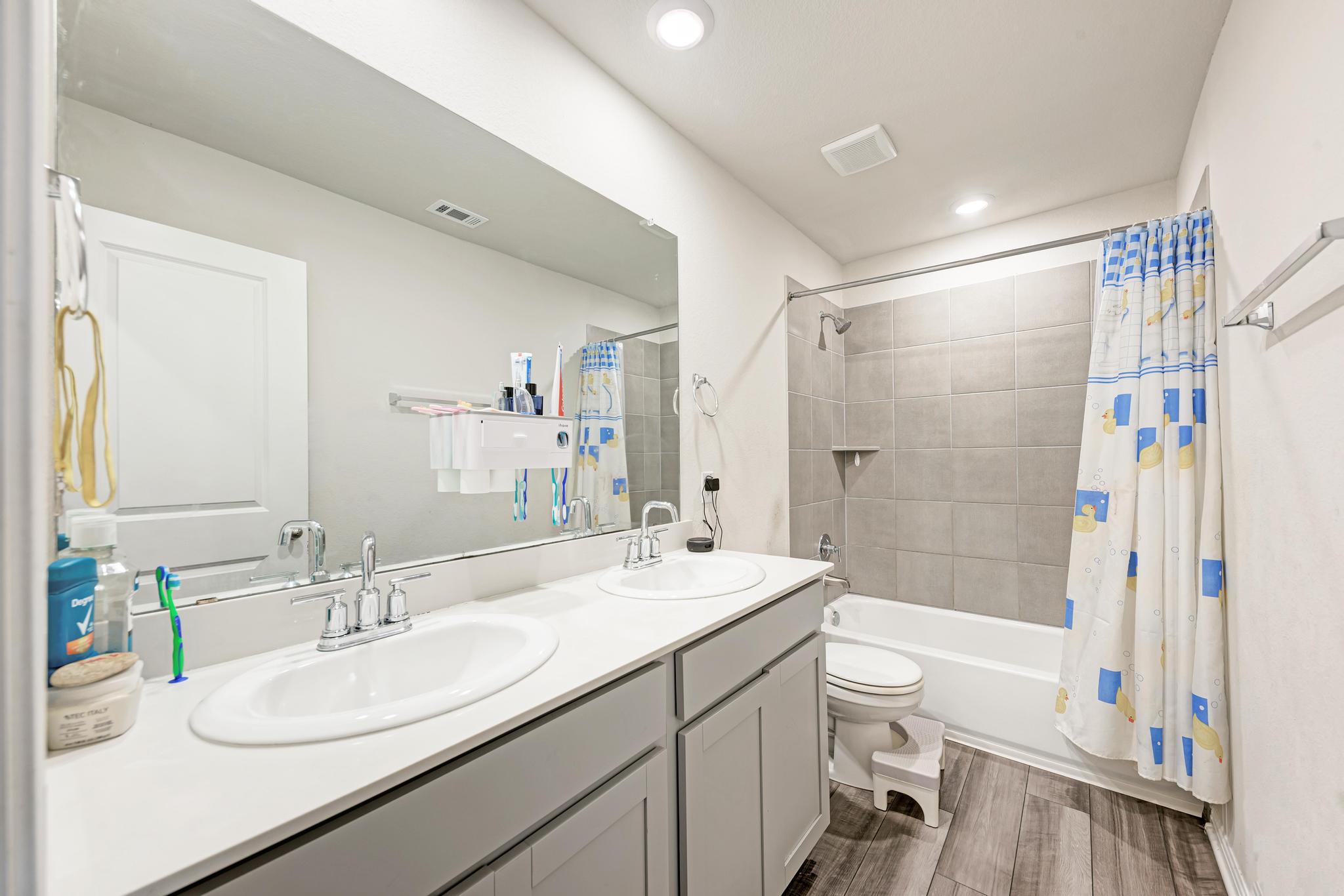 305 Windy Reed Road Hutto, TX 78634 - Photo 23 of 35 A spacious double vanity and tiled tub shower combination define this modern full bathroom.