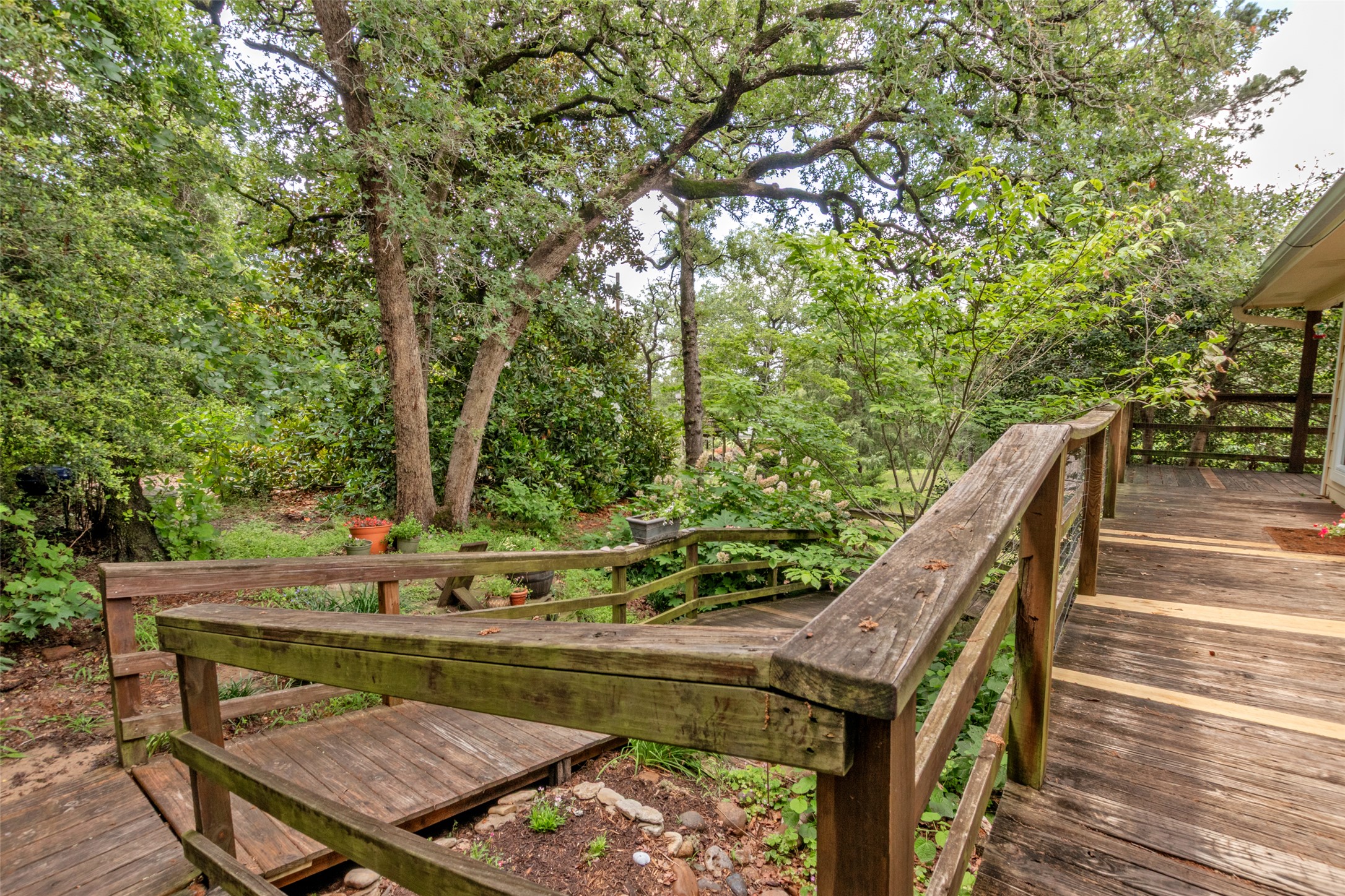 9997 Calhoun Road Bryan, TX 77808 - Photo 23 of 28 Wooden decks and stairs wind through a lush, tree-shaded backyard setting.